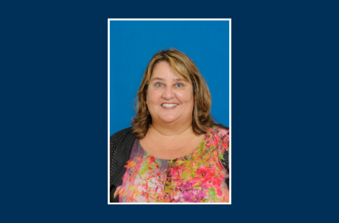 Headshot of an individual on a blue background.