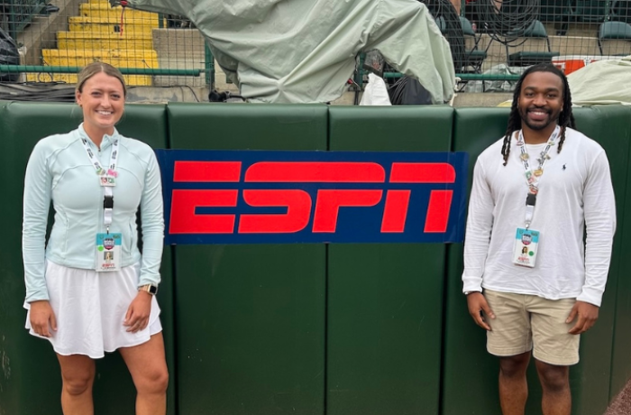 Two people stand in front of a sign that reads "ESPN."