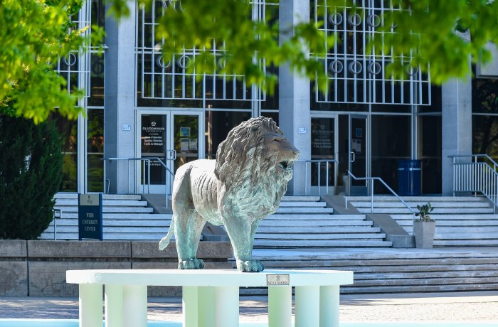 Photo of a college building with a lion statue in front
