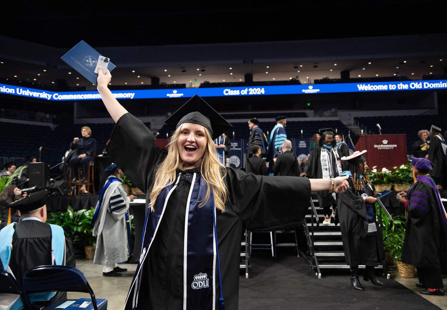 woman with arms raised celebrating after graduating 