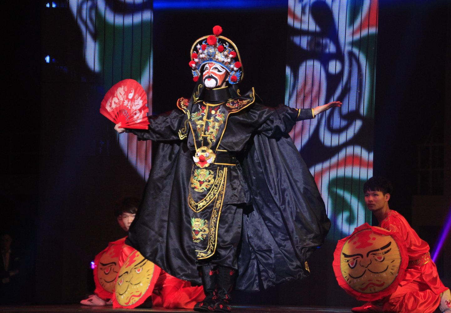 Three performers wear traditional asian attire on stage during theater performance