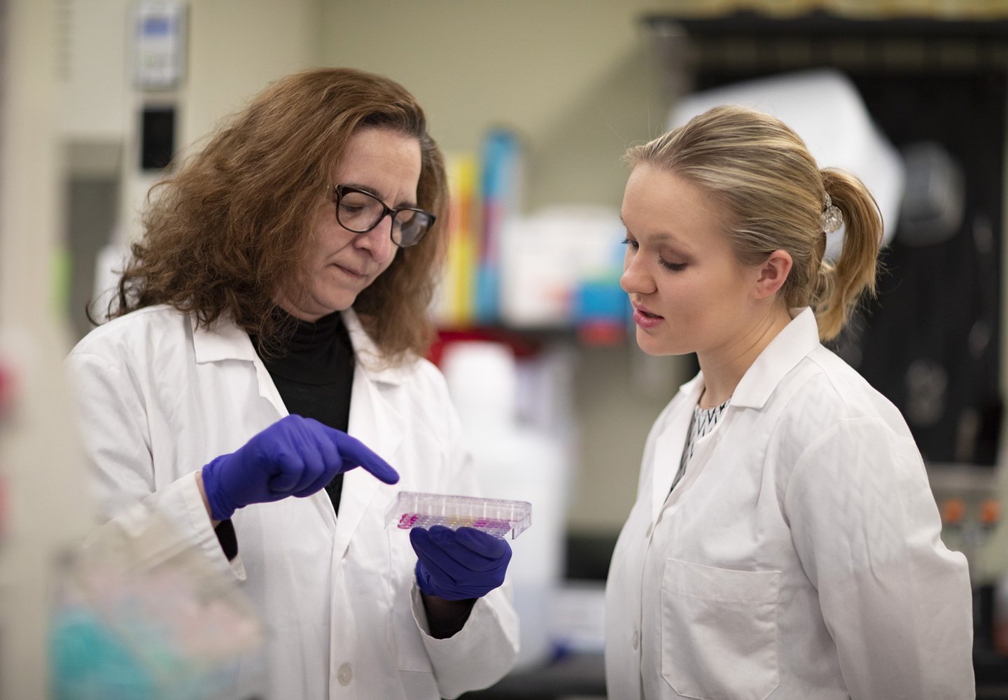 Two women in white coats in a lab