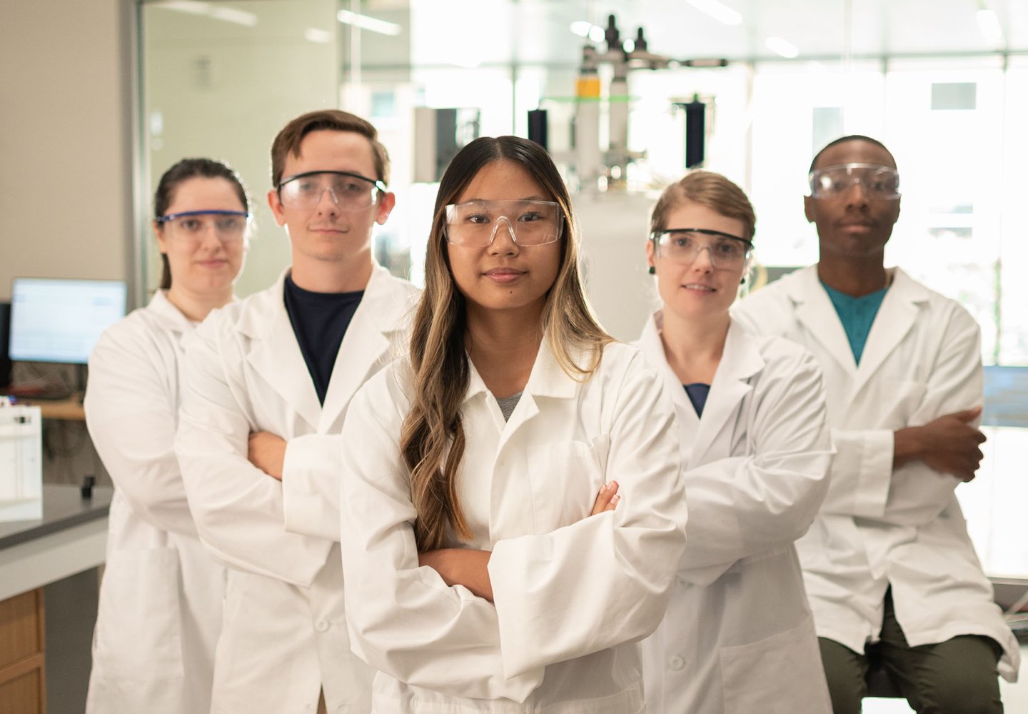 students in white lab coats with arms crossed