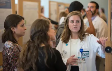 A picture of a medical student explaining her research poste