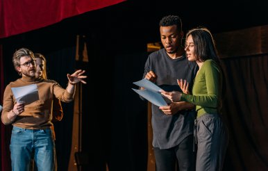 Director and actors rehearse on theatre stage