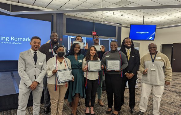 a group of college age students are standing together smiling for a group picture holding up acceptance certificates