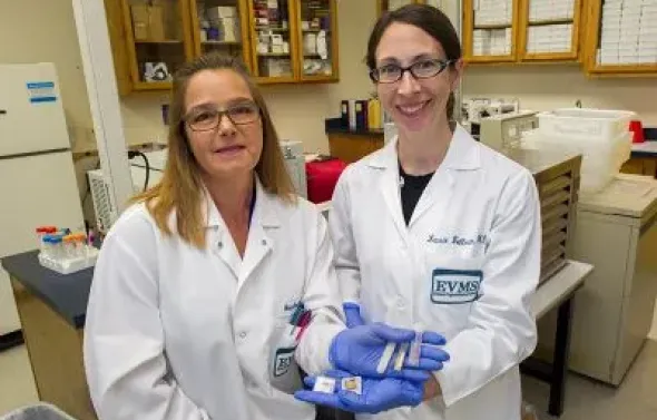 Two biorepository staff face the camera holding out their ha