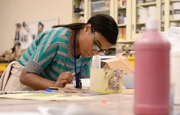 An Art Therapy students creates artwork in the classroom.