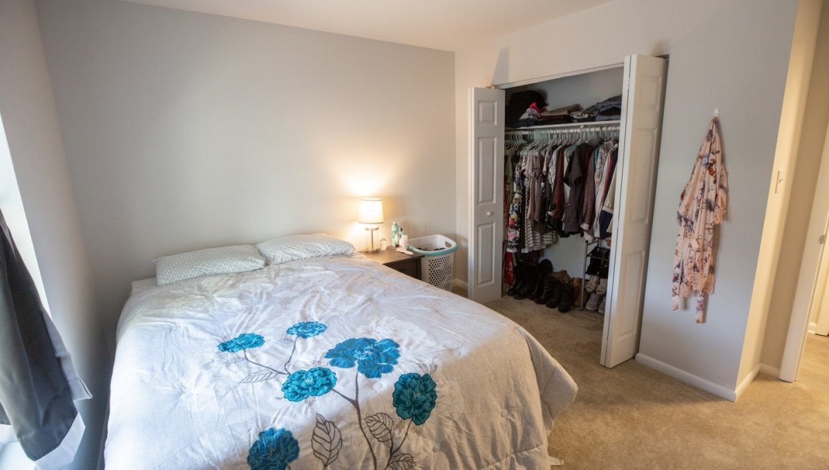 Bedroom with bed, nightstand, and clothes in closet.