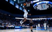 A men's basketball player dunks the ball.