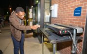 A student points a thermometer at a screen-printing machine.