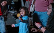 Sonney Canonigo, three, uses a bubble gun to blow bubbles as his aunt, Jordan Asban, and family watches.