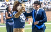 Big Blue with a student on the football field.