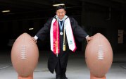 a young man stands next to large footballs 