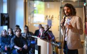 A man speaks into a microphone in front of a group of people.