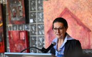 A woman speaks into a microphone at a podium.