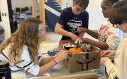 Students working on a cardboard box to make a pumpkin catcher.