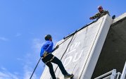 A person rappels down the side of a building.