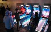 A group of students play arcade games. 