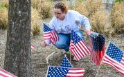 An Old Dominion University student places an American flag on the ground near Dominion Rock, paying tribute to Lt. Col. Brandon Shah (B.S. ’07).