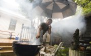 a man stands at a smokey grill 