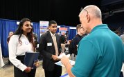Two students listen to a man talk at a career information fair.