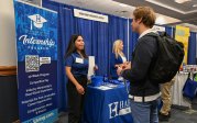 An employer talks with a student at an information table.