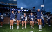 A group of cheerleaders jump and wave. 