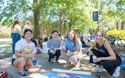 A group of students kneel in front of the crown they've painted on a sidewalk on ODU's campus. 