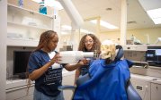 A professor shows a student how to use dental exam equipment.