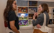 Two people look at a dollhouse.