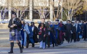 A bagpipes player leads a group of people