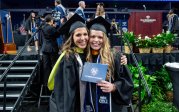 a mother and daughter pose in commencement regalia