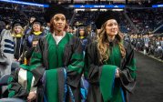 two students pose in commencement regalia