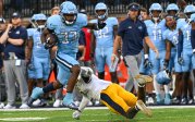 A football player runs past an opponent on the field. 