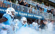 A group of football players exit the tunnel onto the field.