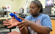 Drew Cox works with parts of a prosthetic device