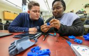 Two people work on a 3D printed prosthetic hand in a lab