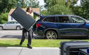 A student carries a refrigerator.