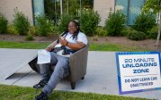 A student sits on a chair outside a residence hall.