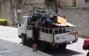 Woman standing beside a truck with chairs in the truck bed.