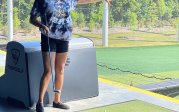 Young woman points to the range at Top Gold before she takes a shot.