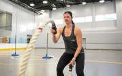 A woman exercises with large ropes.