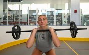 A woman squats with a barbell.