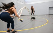 A woman exercises with large ropes. 