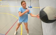 A woman tosses a medicine ball against a wall.