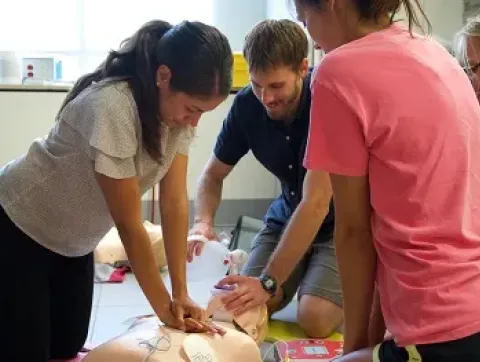 Three students practice performing CPR, and the use of an AE