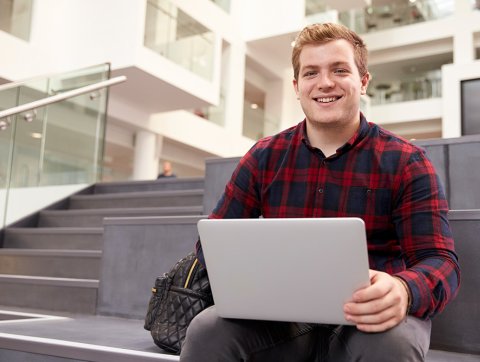 Male university student using laptop