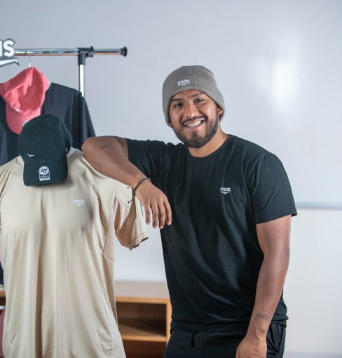 Diego Alonso Cruz Diaz standing next to sport clothing that he designed