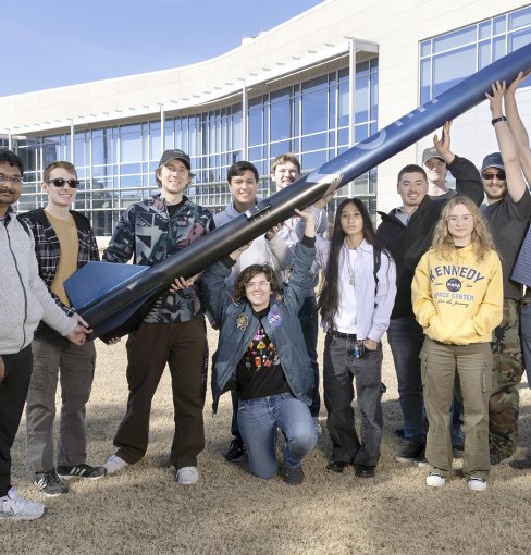 Group of students holding a 10-foot rocket outside